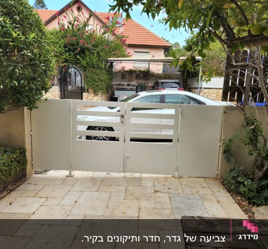 שער מתכת צבוע בלבן בחצר